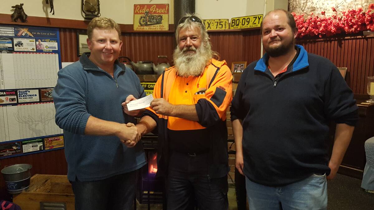 HELPING HAND: Wombat Hotel Social Group president Chris Holmes presented Peter Cockburn and Scott Furner with a donation for their participation in the Redneck Rally next year.