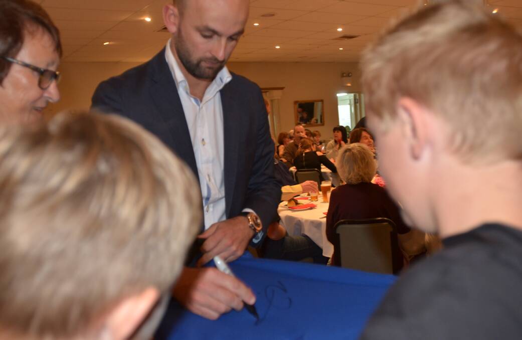 Nathan signing Ethan and Liam Miller's cricket shirts.