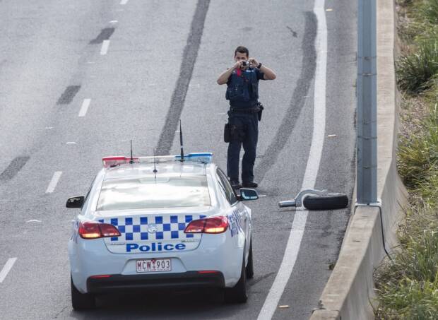 Police investigate the debris on the freeway near to the crash site at Essendon Airport. Photo: Jason South