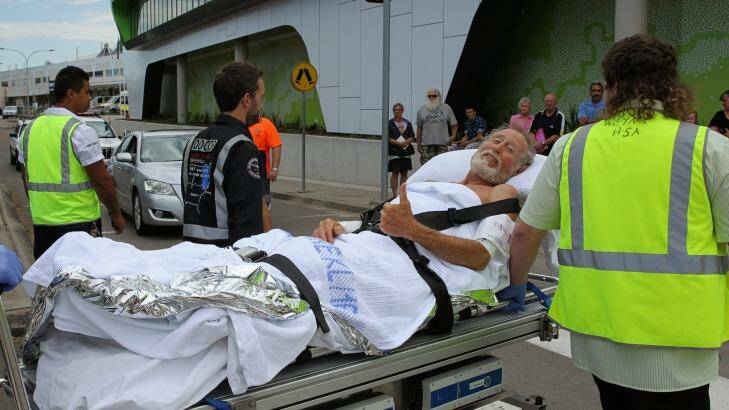 A surfer who was bitten by a shark gives the thumbs up as he is wheeled into John Hunter Hospital. Photo: Max Mason-Hubers
