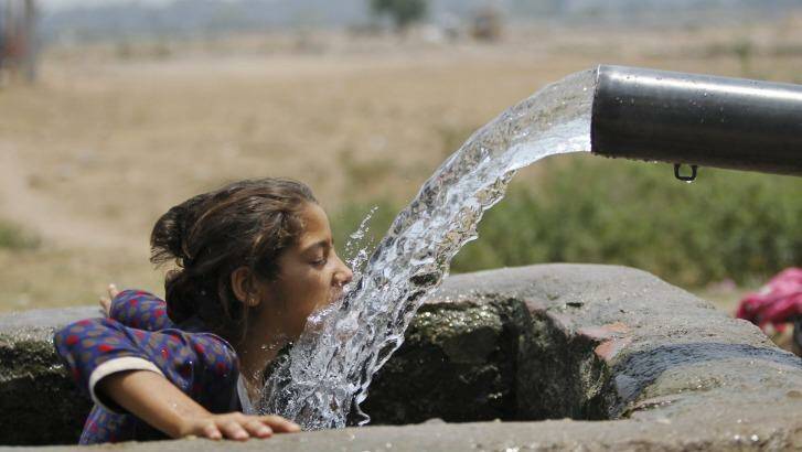 A girl drinks water from an irrigation tube near Jammu last weekend as India's heatwave rolled on. Photo: Channi Annand