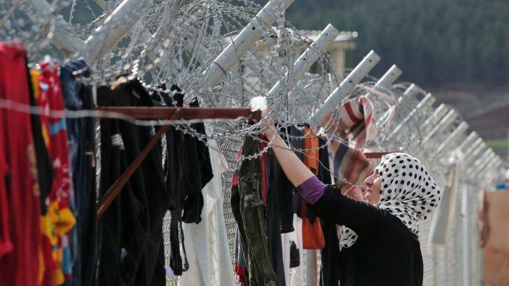 A Syrian refugee hangs clothes to dry on a barbed-wire fence at a refugee camp in Islahiye, Turkey. Photo: Lefteris Pitarakis/AP