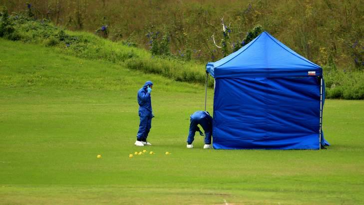 Grisly scene: officers look for evidence on the oval where the body was found. Photo: Simone De Peak
