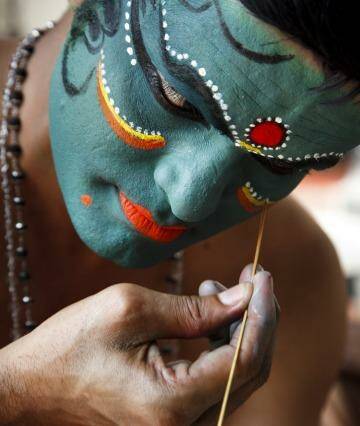 A Kathakali dancer prepares for a performance. The make-up session is one of the attractions of the event.