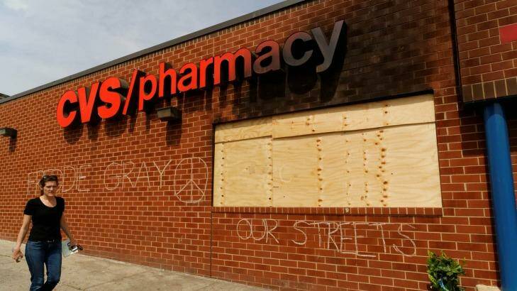 A woman walks past a Baltimore pharmacy looted during the protests over the death of Freddie Gray. Photo: Trevor Collens