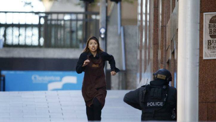 A Lindt worker believed to be Elly Chen flees the cafe.  Photo: Jason Reed/Reuters