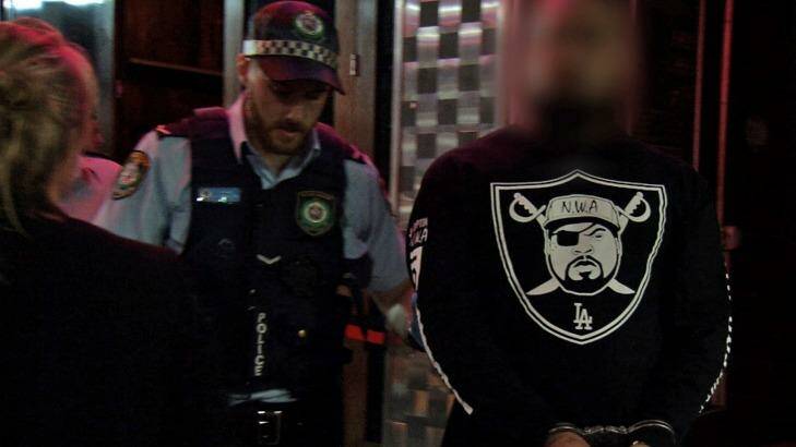 An man is taken away by police outside Bada Bing during raids in December. Photo: NSW Police Media