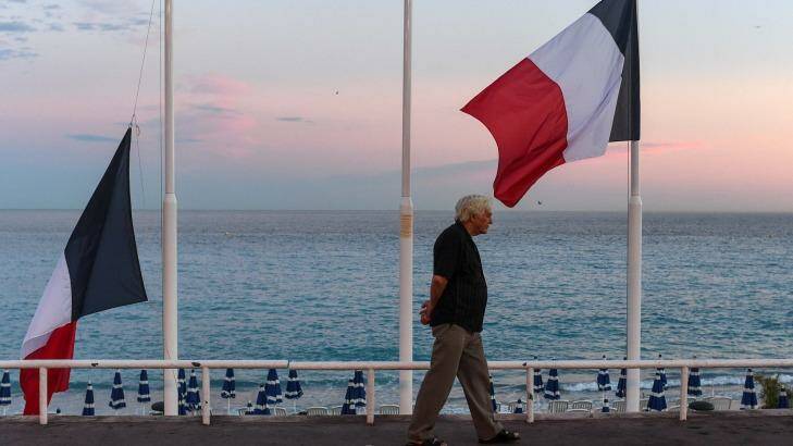 A man walks past French flags flying at half-mast on the Promenade des Anglais in Nice, France, the day after a French-Tunisian attacker killed 84 people as he drove a lorry through Bastille Day crowds. Photo: David Ramos