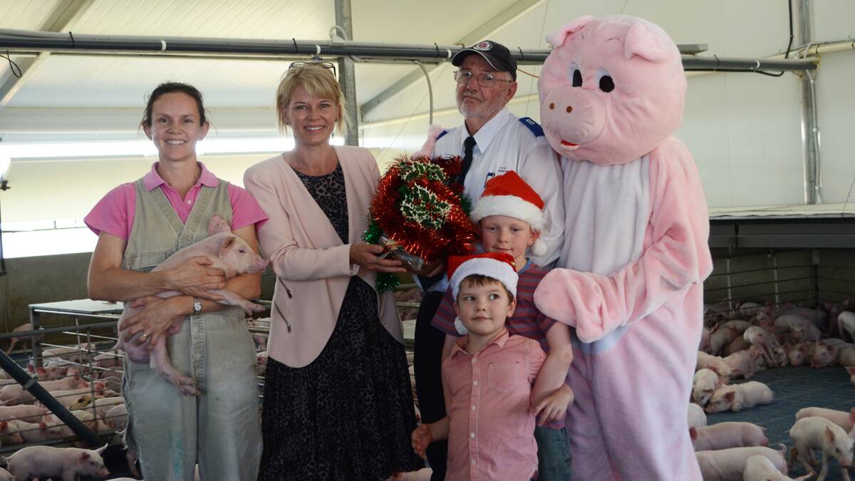 HAND OVER: Andreo Rowntree, Katrina Hodgkinson, Salvation Army's Laurie Anderson, Tom Rowntree (older child), James Rowntree (younger child), and Mr Dugald Walker pictured in the four-week-old piglets shed at the Wonga farm. 			(hamover (4)