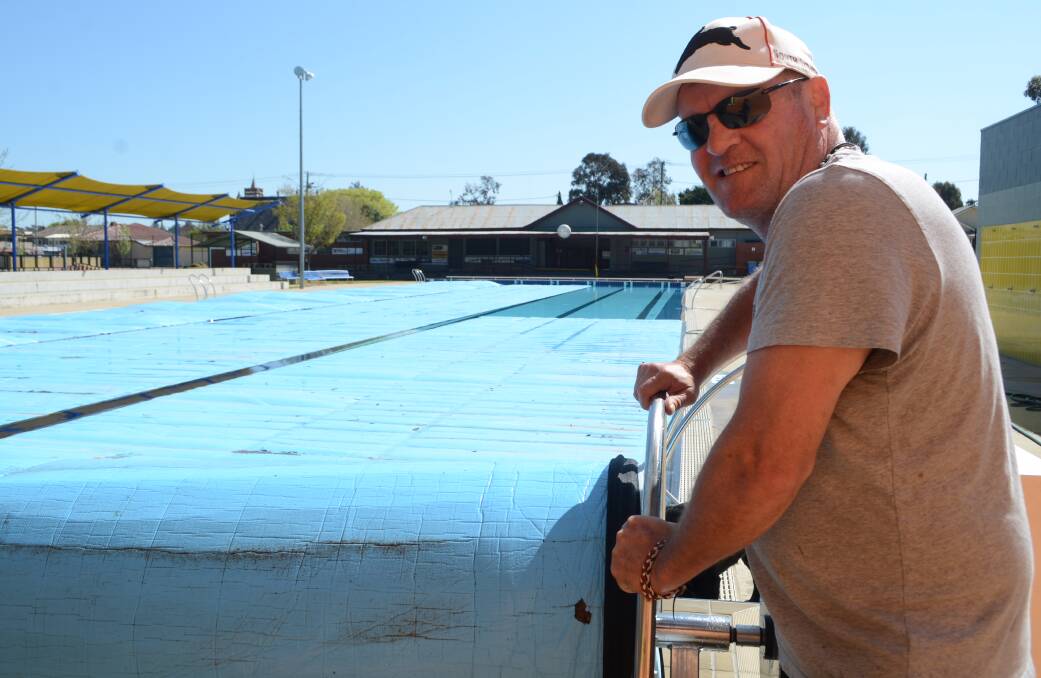 HOP IN THE WATER'S FINE! Young pool manager Paul 'Viince' Vitnell unrolling the pool covers ahead of tomorrow's opening.