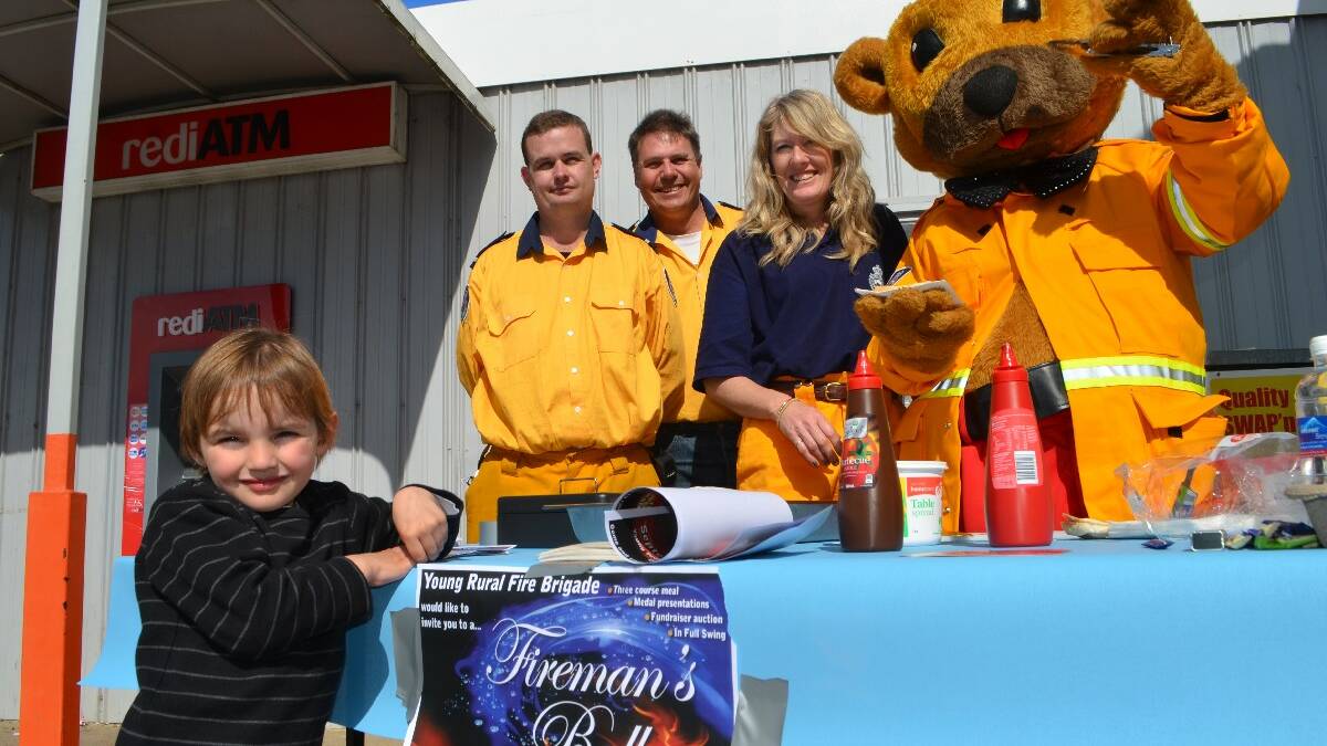 RAISING AWARENESS: Determined to spread the word about September’s fireman’s ball, firefighters Max Long, Steve Warwick, Louise Livermore and their dear friend Fred the Fireman Bear hosted a barbecue last Saturday morning. Four-year-old Hayden Lobb was keen for a snag on the day.