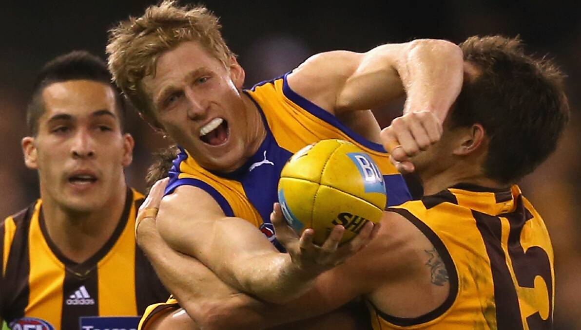 Scott Selwood of the Eagles handballs whilst being tackled by Luke Hodge of the Hawks. Photo: Getty Images.