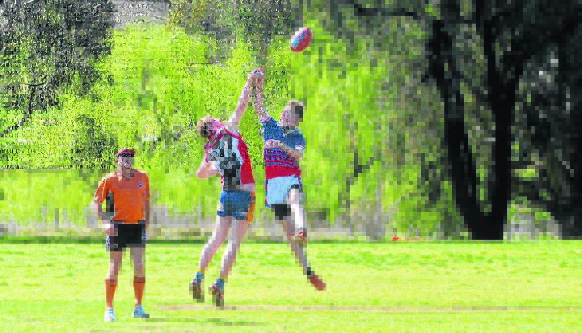 CLOSE GAME: Umpire Geoff Harmer watches Will Quinn from Hennessy Catholic College (left) and Nick Schiller from Young High fight for the ball in the senior boys’ match last Friday. 