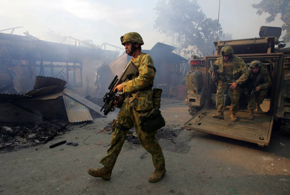 Australian peacekeeping soldiers walk through the smoke from an entire block of burning homes on June 5, 2006 in Dili, East Timor. Photo by Paula Bronstein /Getty Images