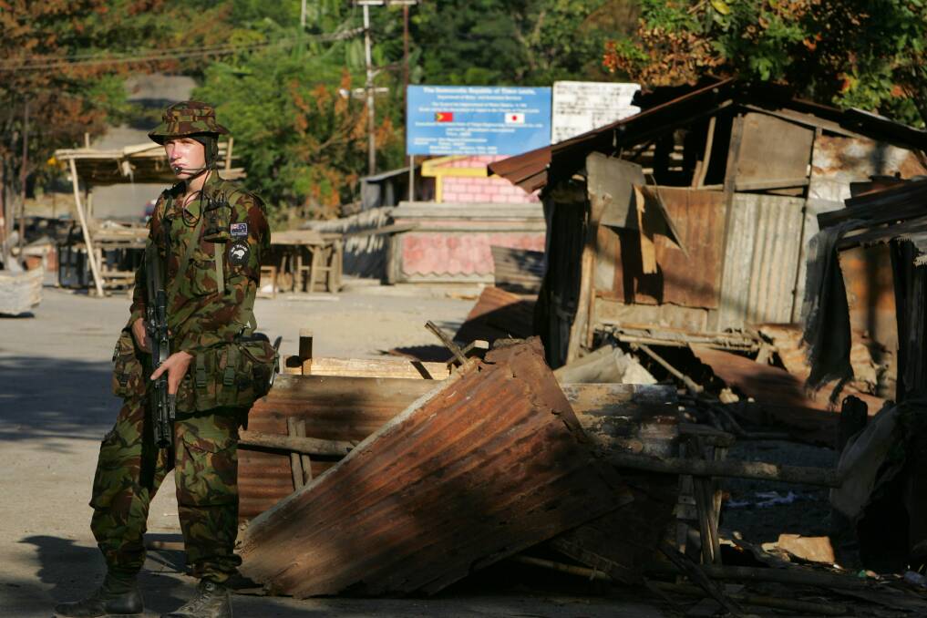 A New Zealand peacekeeper stands guard at a checkpoint next to a burnt-out market on June 3, 2006 in Dili, East Timor. Photo by Paula Bronstein/Getty Images