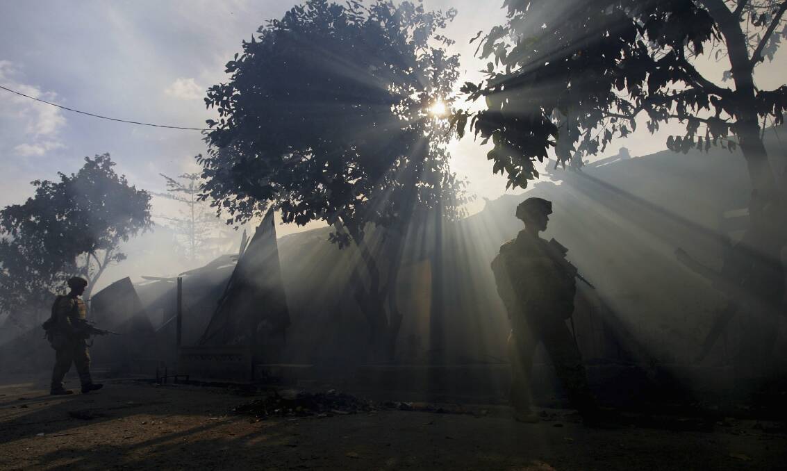 Australian peacekeeping soldiers patrol through the smoke from an entire block of burning homes on June 5, 2006 in Dili, East Timor. Photo by Paula Bronstein /Getty Images