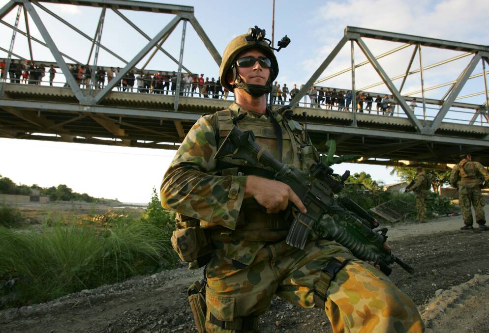 An Australian peacekeeping soldier stands guard next to the river after violence broke out between feuding gangs June 3, 2006 in Dili, East Timor. Photo by Paula Bronstein/Getty Images