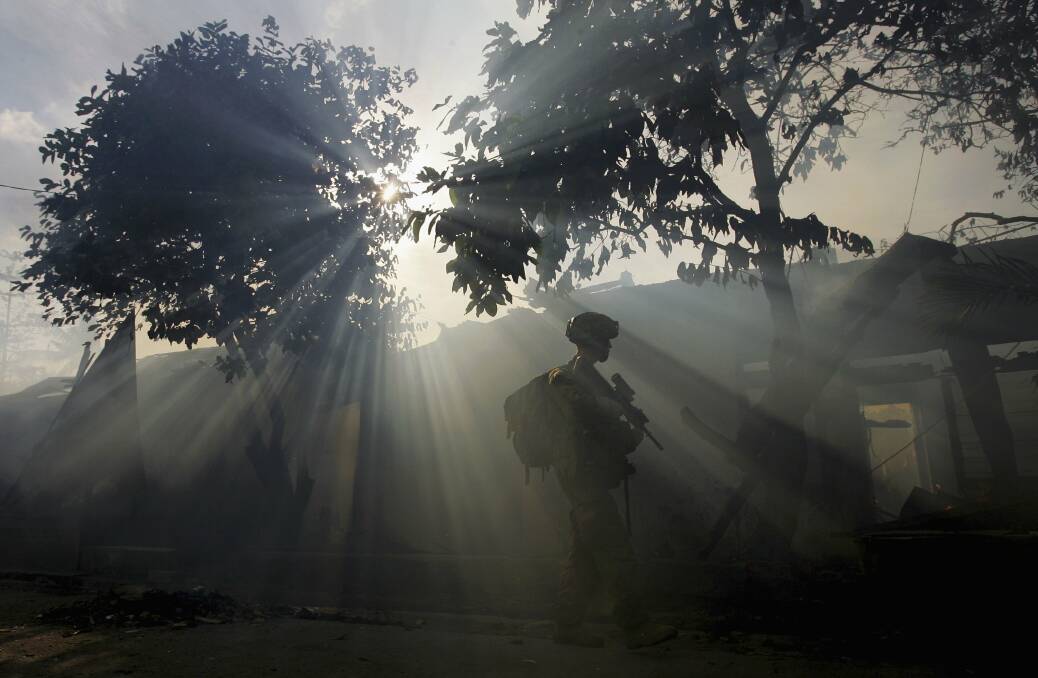 Australian peacekeeping soldiers patrol through the smoke from an entire block of burning homes with Graffiti on a walls depicting death, June 5, 2006 in Dili, East Timor. Photo by Paula Bronstein /Getty Images