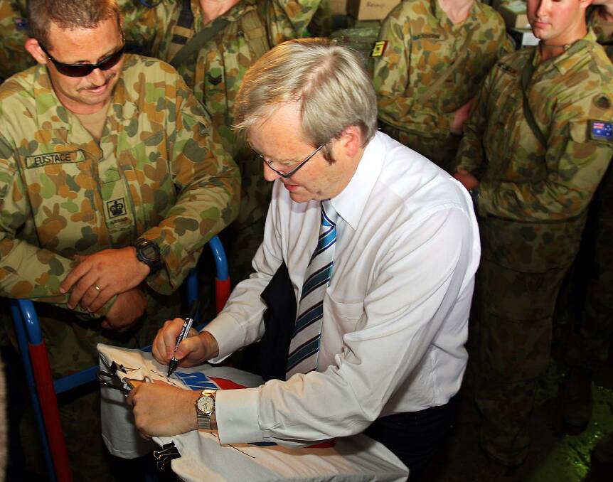 Australian Prime Minister Kevin Rudd signs a t-shirt during his visit to the International Security Forces (ISF) at Heliport February 15, 2008 in Dili, East Timor. Photo by Luis Enrique Ascui/Getty Images