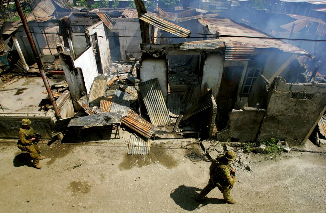 Australian peacekeeping troops walk by a house fire on June 4, 2006 in Dili, East Timor. Photo by Paula Bronstein/Getty Images