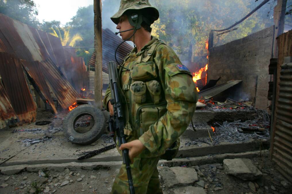 Australian peacekeeping soldiers walks by a fire at a house, torched by alleged gang violence June 7 , 2006 in Dili, East Timor. Photo by Paula Bronstein/Getty Images