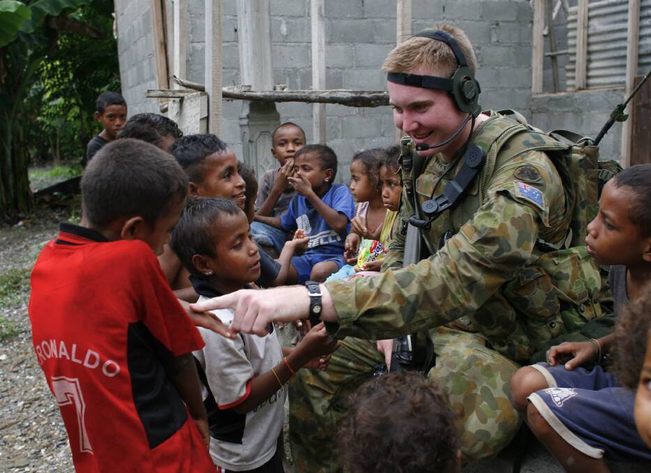 Australian peacekeeper Private Tim Hunt-Smith from New South Wales plays with East Timorese children while on patrol April 10, 2007 in Dili, East Timor. Photo by Paula Bronstein/Getty Images