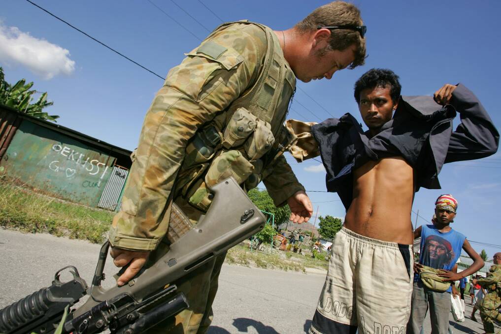 An Australian peacekeeping soldier searches a gang member for weapons after violence erupted June 5, 2006 in Dili, East Timor. Photo by Paula Bronstein/Getty Images