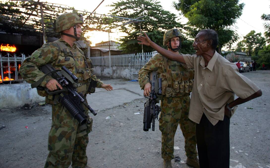 Australian peacekeeping soldiers try to calm down a home owner as his house burns on June 5, 2006 in Dili, East Timor. Photo by Paula Bronstein /Getty Images