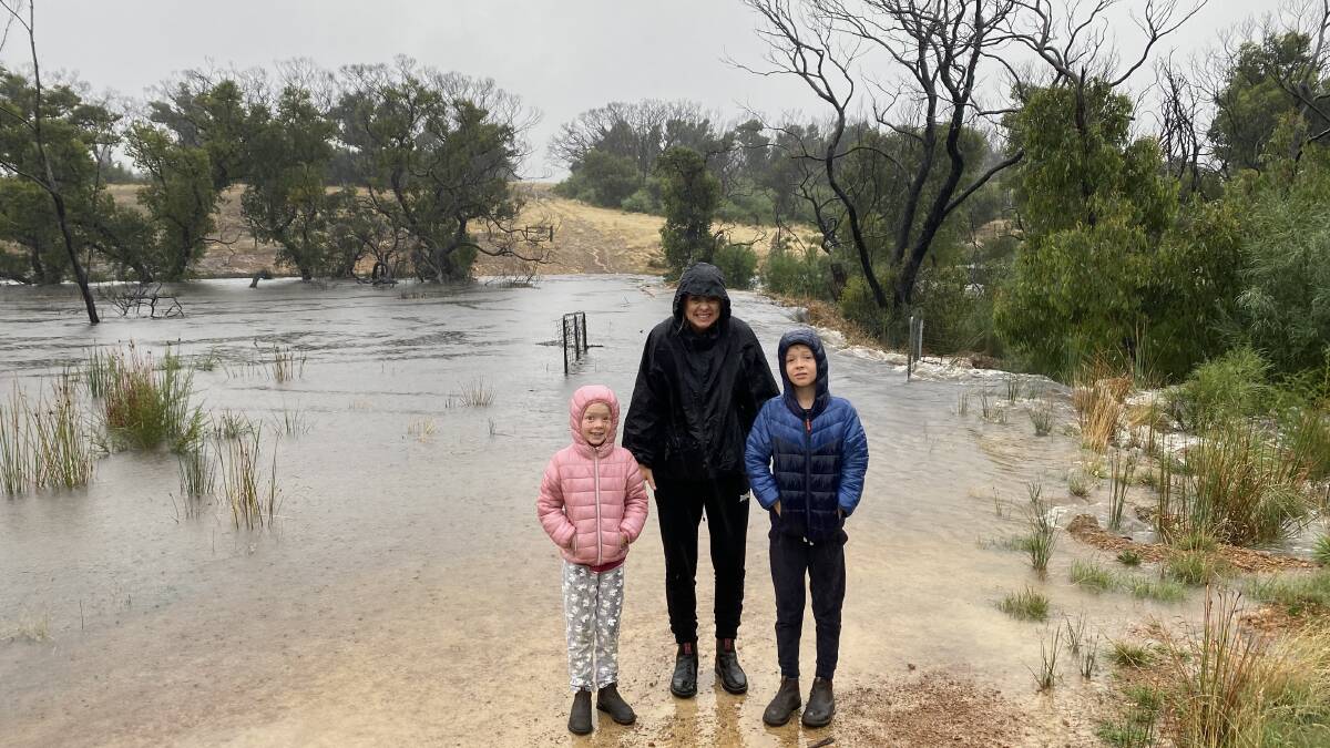 Sabrina Davis (centre) and her children stand in front of their flooded dam at Gosse on Kangaroo Island. Photo: Sabrina Davis