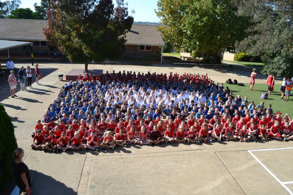 RED, WHITE AND BLUE: Primary students at Young Public School dressed in the colours of the Laos flag before creating the flag to raise money for their foster child from the country.