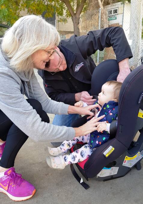 Phil Pallister, the Authorised Restraint Fitter, showing Denise how to adjust and check the straps for fit on Halle's car seat.