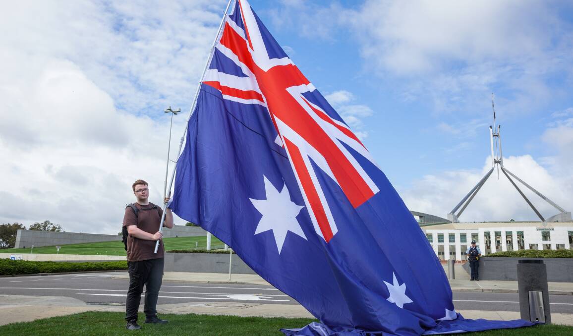 Zach Hook and his enormous Australian flag at the demonstration. Picture by Sitthixay Ditthavong
