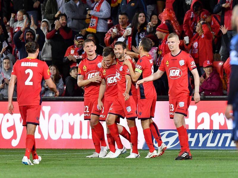 Adelaide United players celebrate Scott Galloway scoring the opening goal of the A-League season.