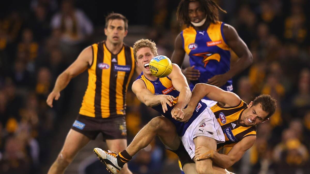 Scott Selwood handballs whilst being tackled by Luke Hodge. Photo: Getty Images.