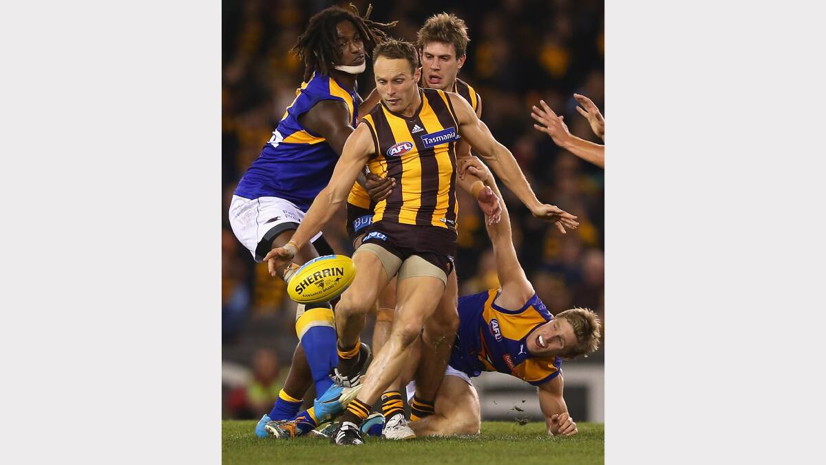Brad Sewell kicks Hawthorn forward whilst being tackled by Nic Naitanui. Photo: Getty Images.